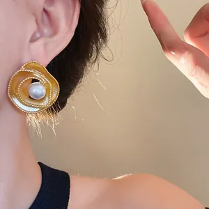 Elegant vintage spiral gold-tone stud earrings with center faux pearl detail on model