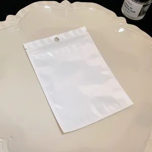 Close-up of a white pearlized ziplock bag on a cream decorative plate for jewelry.
