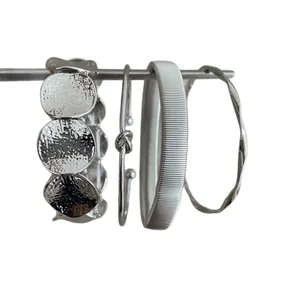 Set of 4 silver geometric metal bracelets with textured and knotted designs