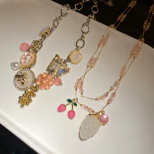 Detail view of elegant crystal and enamel pendant necklaces with butterfly and strawberry charms.