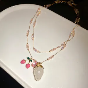 Detail of beaded necklace with white strawberry and pink cherry pendants.