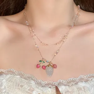 Close-up of a double-layered crystal necklace with strawberry and cherry pendants