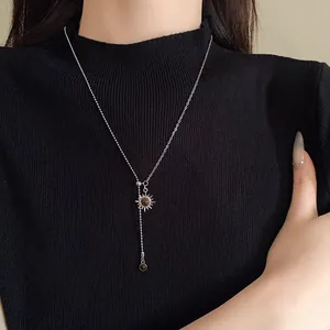 Detailansicht einer silbernen Sonnenhalskette mit Tigerauge-Stein auf einem schwarzen Pullover.