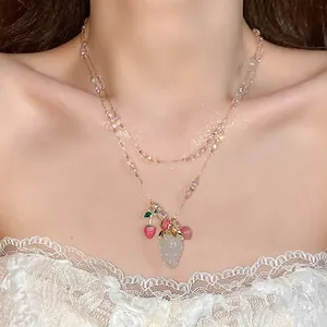 Detail view of a double-layer necklace with crystal strawberry and cherry pendants.