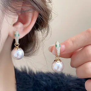 Detailed view of elegant snake-shaped earrings featuring pearls and crystal pavé on ear.