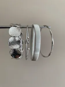 Detailed view of four minimalist silver geometric bangles with varied textures