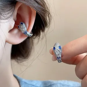 Detailed macro view of silver snake ear cuff featuring blue crystal eyes and pavé diamonds.