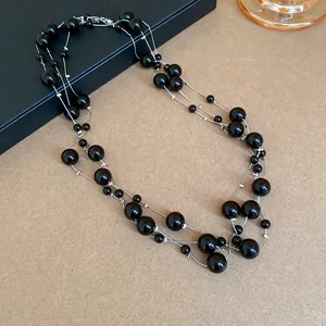Detailed view of elegant multi-layer long necklace with black pearls and silver chains