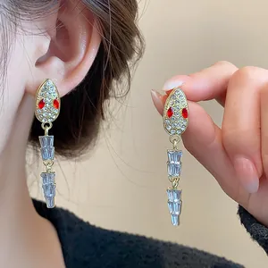 Detail view of elegant gold-tone snake earrings with crystal pavé and red eyes