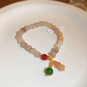 Detailed macro shot of a handmade stone beaded bracelet featuring an elegant gourd pendant