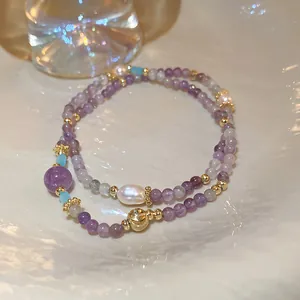 Close-up detail of handmade purple beaded bracelet featuring pearls and gold spacers
