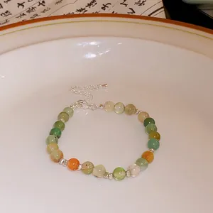Macro view of a handmade beaded bracelet with green and orange semi-precious stones