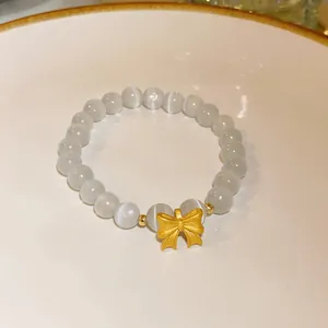Close-up detail of a handmade beaded bracelet featuring a golden bow charm on white plate