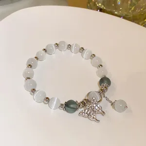 Close-up of handmade white cat's eye bead bracelet with sparkling butterfly charm