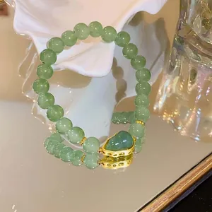 Detailed view of a green strawberry crystal beaded bracelet with a gourd charm