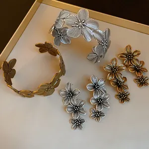 Macro view of vintage silver and gold floral drop earrings and cuff bracelets