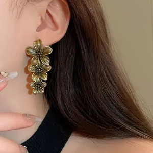 Exquisite close-up view of vintage golden three-layer flower drop earrings worn by a model