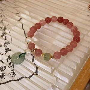 Handmade strawberry quartz beaded bracelet with pearl and green jade donut charm.