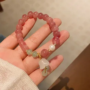 Close-up detail of a handmade strawberry crystal bracelet featuring a white lily charm