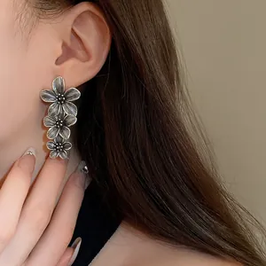 Close-up detail of vintage silver-toned flower drop earrings worn on a model ear