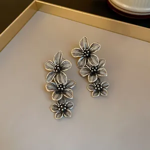 Detail of vintage oxidized silver triple flower drop earrings with textured petals