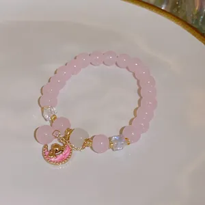 Close-up of pink beaded bracelet with delicate golden moon and rabbit charm detailing.