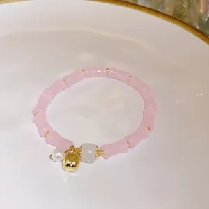 Macro view of pink bamboo-shaped beaded bracelet featuring a golden apple charm detail.