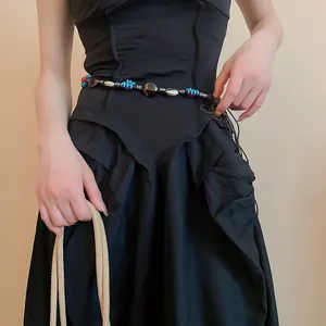 Close-up of bohemian leather waist chain with turquoise beads and shells on black dress
