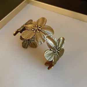 Detailed macro view of an antique gold flower cuff bracelet showing textured metal petals
