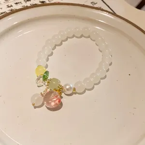 Detailed shot of a handmade beaded bracelet with strawberry quartz on a white ceramic plate