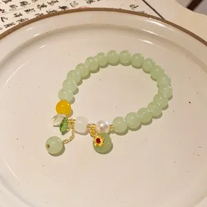 Detail view of a New Chinese style beaded bracelet with green beads and pearl charms.