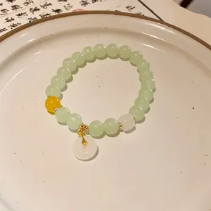 Detail view of a handmade New Chinese style beaded bracelet with a white jade-like donut charm