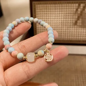 Close-up of a handmade strawberry quartz beaded bracelet with a clover pendant