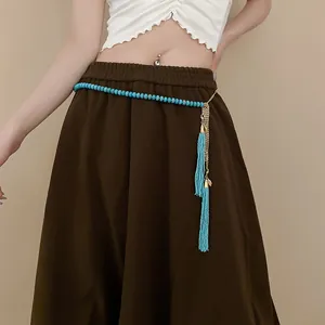 Detail view of Bohemian turquoise bead waist chain with golden tassels on a brown skirt