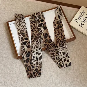 Stylish leopard print silk scarf ribbon necklace displayed on a minimalist wooden tray.