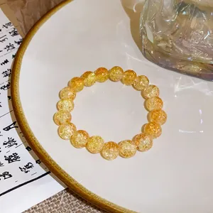 Close-up of handmade yellow strawberry crystal beaded bracelet on white ceramic plate