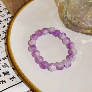 Detailed macro view of purple crackle crystal beaded bracelet resting on elegant ceramic plate
