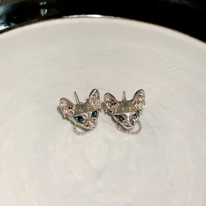 Detailed macro view of silver cyberpunk Sphynx cat stud earrings with blue gem eyes