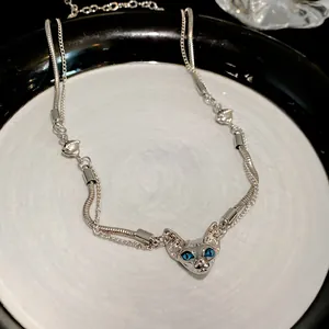 Macro detail view of a cyberpunk Sphynx cat head necklace with bright blue eyes
