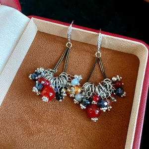 Close-up of Bohemian earrings with colorful beads and zircon hooks in a gift box