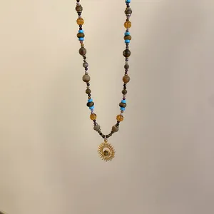 Primo piano di una collana di perle vintage con un ciondolo a sole dorato chic