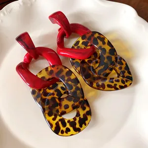 Close-up of leopard print link earrings with red marble accents on a white plate