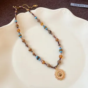 Dettaglio di una collana in acciaio inossidabile con ciondolo a sole e perline etniche