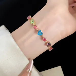 Gros plan d'un bracelet en zircon coloré en forme de cœur sur une chaîne dorée