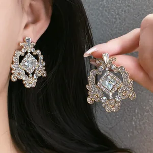 Detailed view of ornate French vintage style hollow rhinestone earrings on model