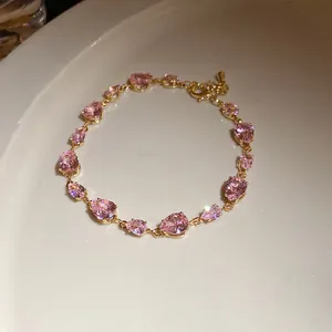 Vue détaillée d'un bracelet doré élégant serti de pierres de zircon roses en forme de poire.