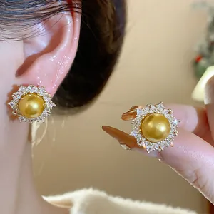 Detailed view of elegant gold pearl earrings with a sparkling zircon halo design on ear