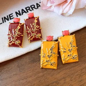 Detail view of vintage Chinese style enamel earrings with gold branch relief and pink stones.