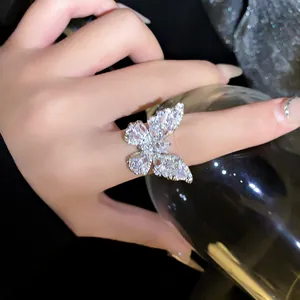 Detailed macro shot of a sparkling zircon butterfly ring worn on a hand holding a glass.