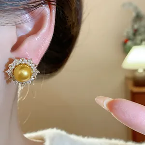 Macro view of luxury French-style golden pearl earring with sparkling zircon halo detail